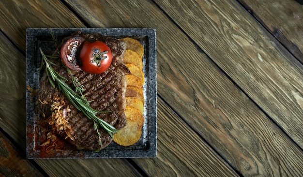 Bistec a la parrilla con cuchillo y tenedor tallado en pizarra de piedra negra Bistec en una piedra de mármol caliente Copia espacio fondo oscuro comida moda foto