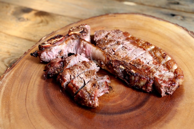 Bistec a la parrilla con hueso y dos tipos de carne Sobre fondo de madera