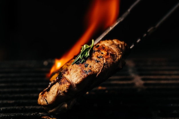 Bistec a la parrilla con llamas. Filete de ternera cruda en una parrilla de barbacoa. banner, menú, lugar de receta para texto, vista superior.