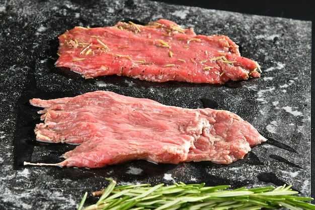 Foto un bistec en una pizarra con una ramita de romero.