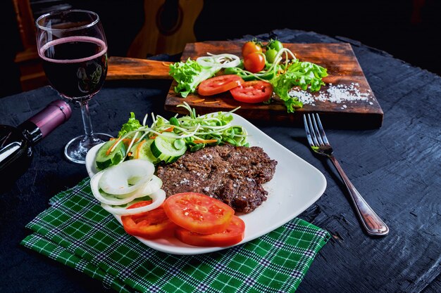 Bistec a la plancha y vino tinto sobre la mesa.