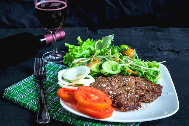 Bistec a la plancha y vino tinto sobre la mesa.