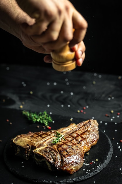 Bistec Porterhouse a la parrilla. El chef sazona la sal en un jugoso filete de ternera en un restaurante. en un movimiento congelado