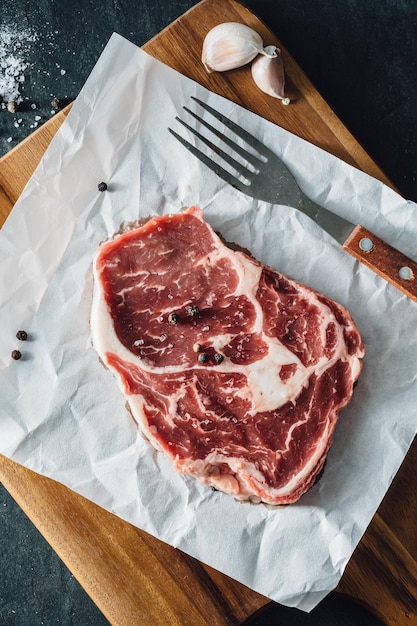 bistec de ribeye con tabla de cortar de madera sobre un fondo negro de piedra