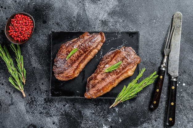 Bistec de tapa de rampa a la parrilla sobre una tabla de cortar de piedra. Vista superior.