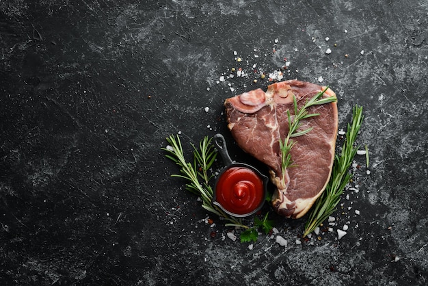 Bistec Tbone crudo sobre una mesa de piedra negra Vista superior Espacio libre para el texto