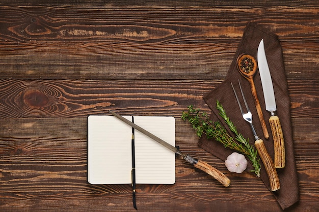 Bistec tenedor cuchillo y afilador en mesa de madera junto al portátil