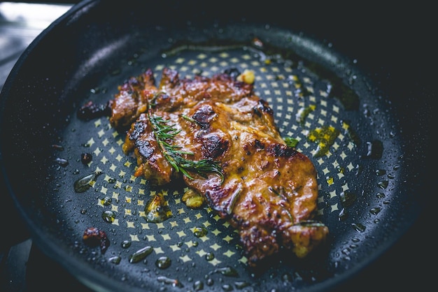 Bistec de ternera cocido con romero y ajo dentro de una sartén de hierro