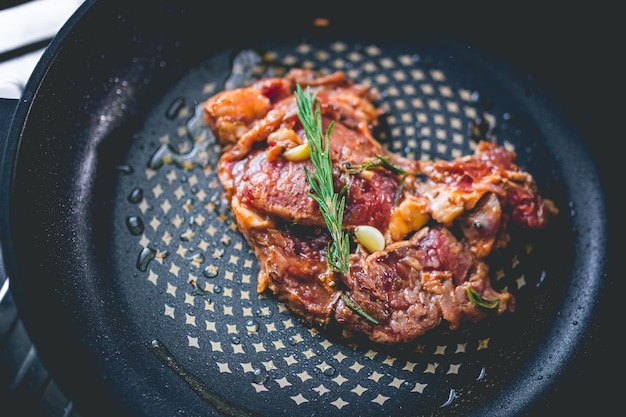 Bistec de ternera cocido con romero y ajo dentro de una sartén de hierro