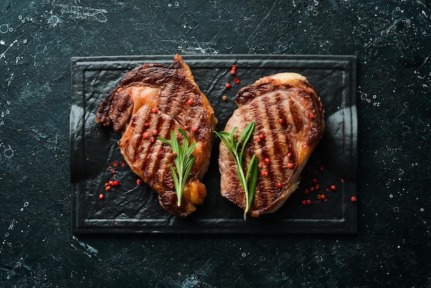 Bistec de ternera a la parrilla con especias en una mesa de piedra negra Vista superior Espacio libre para el texto