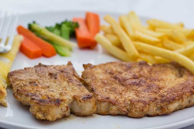 Bistec de ternera con verduras y patatas fritas en un plato