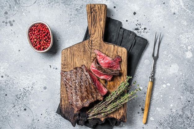 Bistec de venado salvaje a la parrilla sobre tablero de madera Fondo gris Vista superior