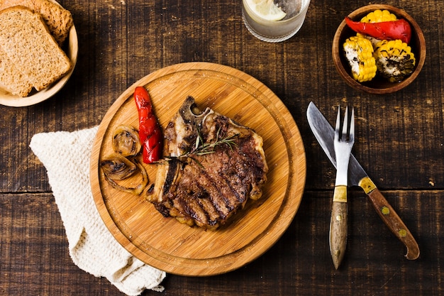 Foto bistec con verduras en tablero redondo.