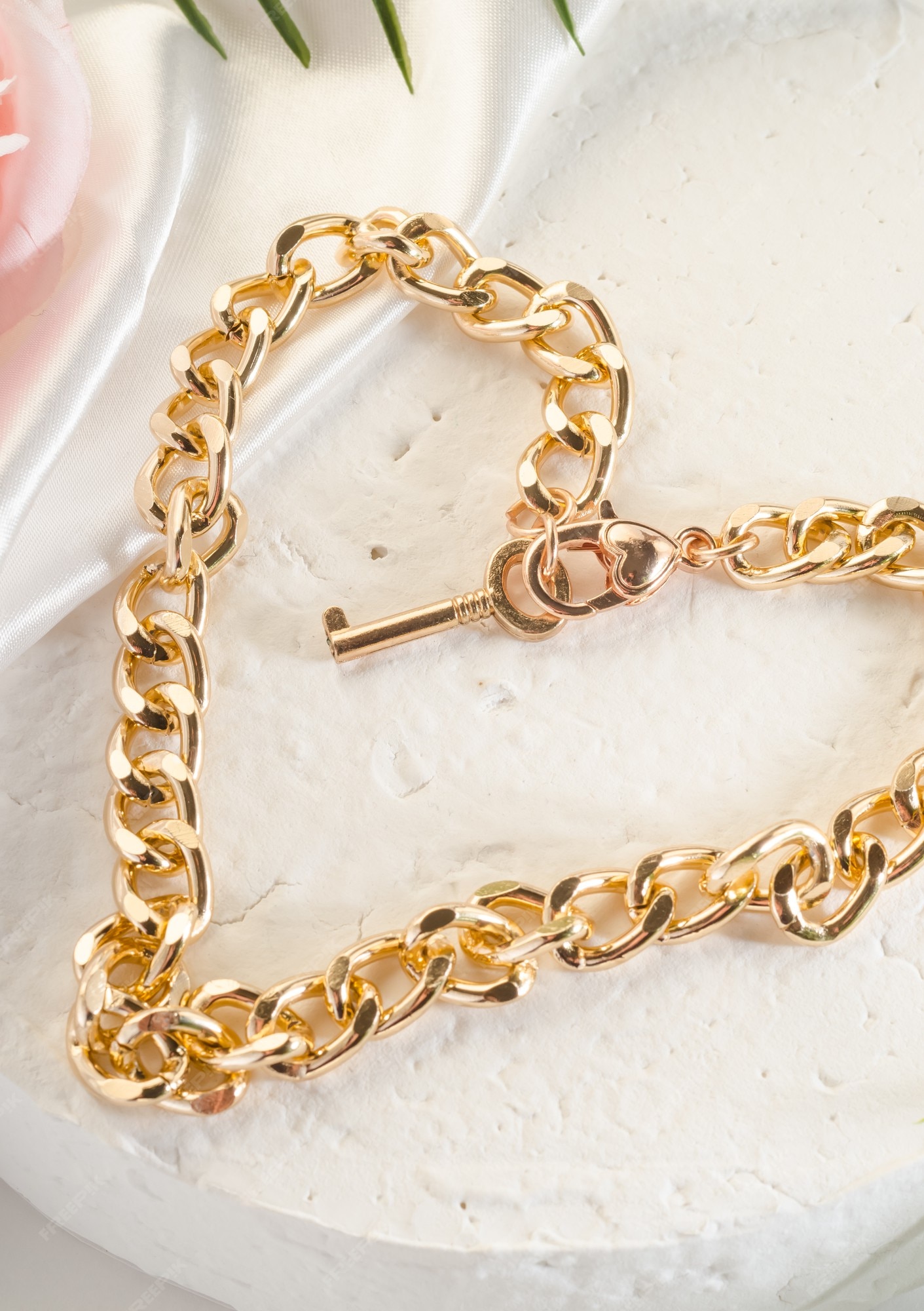 Bisutería moda: gran pulsera de cadena de oro un corazón y un candado en un soporte blanco | Foto Premium