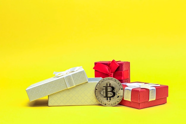 Bitcoin als Geschenk. Investitionsgeschenk Bitcoin-Münze in einer Geschenkbox auf gelbem Grund. Postkarte zum Drucken, Banner mit Platz für Text.