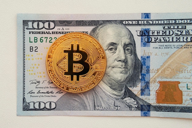 Bitcoin auf 100-Dollar-Schein Hintergrund Goldmünze von Bitcoin auf einem Hundert-Dollar-Schein