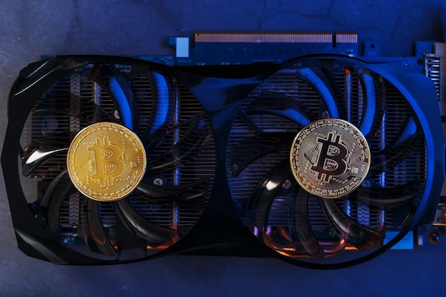 Bitcoin auf einer Grafikkarte mit blauem Neonlicht auf dunklem Hintergrund. Kryptowährungs-Mining-Konzept