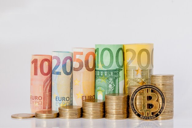 Bitcoin y diez, veinte, cincuenta, cien, doscientos y monedas billetes enrollados en euros billetes en blanco