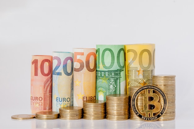 Bitcoin y diez, veinte, cincuenta, cien, doscientos y monedas billetes enrollados en euros