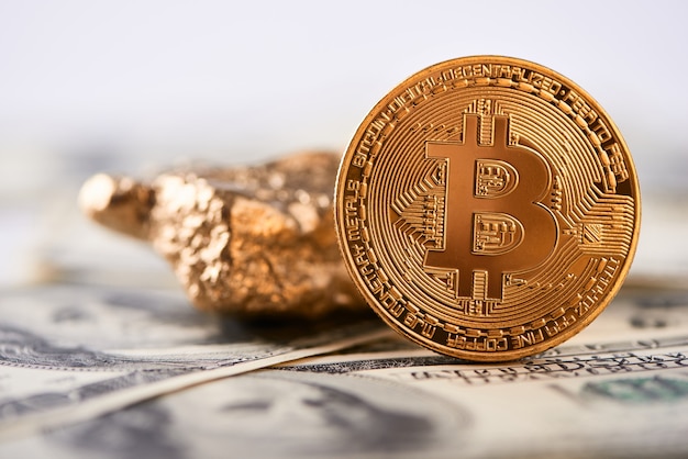 Bitcoin dorado brillante y bulto de oro puestos en billetes de dólares y representan nuevas tendencias financieras.