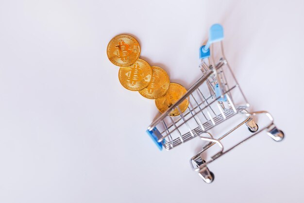 Bitcoin dorado en un carrito de compras sobre un fondo blanco. Vista desde arriba. Concepto de compra de criptomonedas