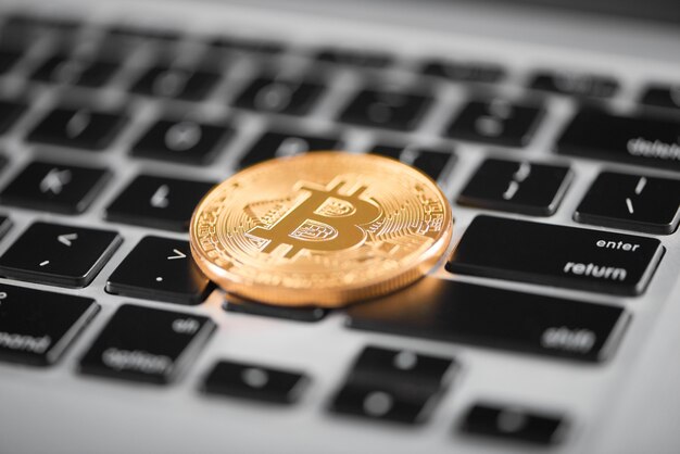 Foto un bitcoin dorado como la principal criptomoneda del mundo colocada en el teclado de una computadora portátil.