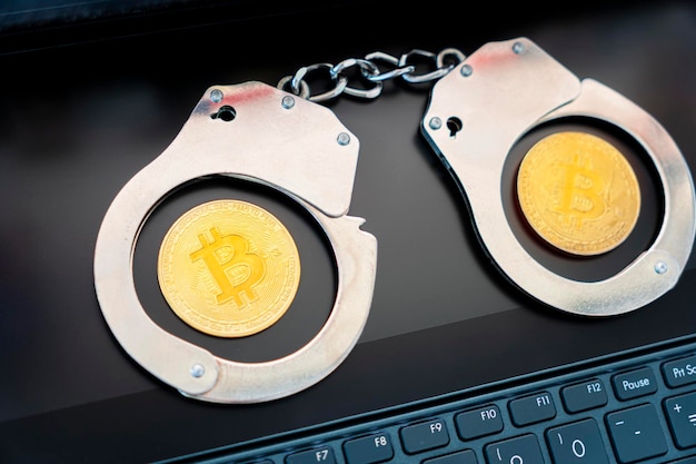 bitcoin dorado en el fondo de esposas y un teclado de computadora portátil negro Prohibición de la venta y compra de bitcoin y criptomonedas