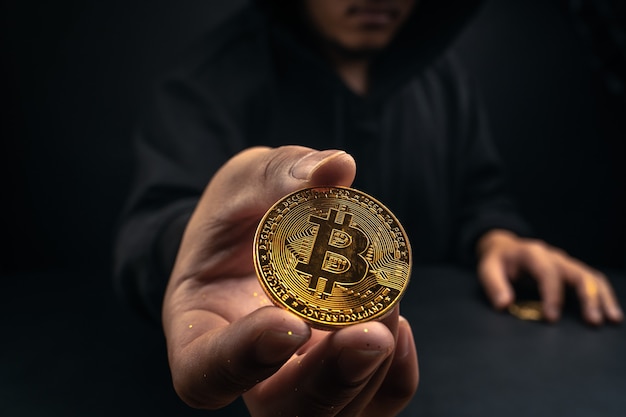 Un bitcoin dorado en la mano de un hombre misterioso, finanzas digitales