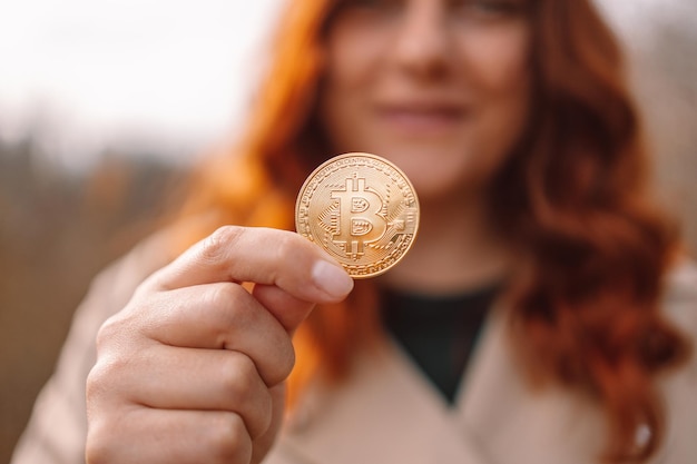 Bitcoin dorado en una mano de mujer de negocios al aire libre concepto de criptomoneda