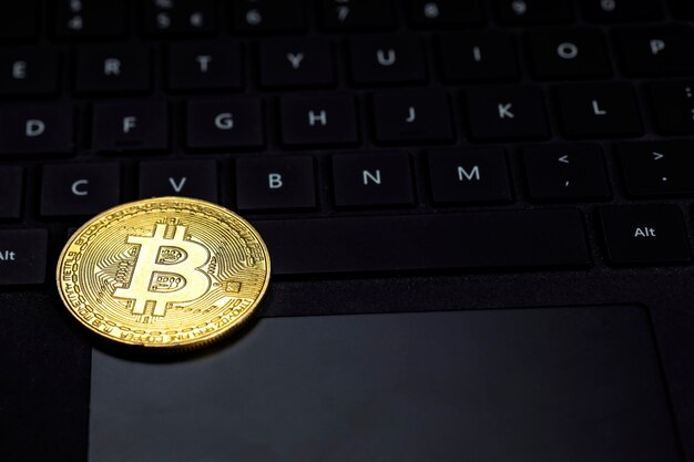 Un bitcoin dorado en el teclado negro oscuro del concepto de tecnología y comercio de divisas criptográficas de la computadora ...