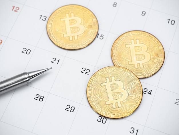 Bitcoin dourado e caneta na vista superior do calendário
