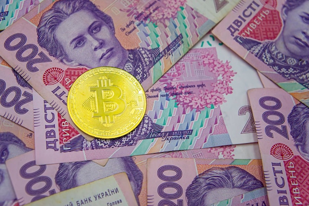 Bitcoin dourado em fundo de duzentas contas hryvnia ucranianas