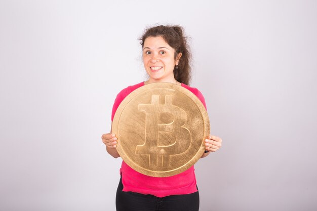 Bitcoin dourado na mão de uma mulher, símbolo digital de uma criptomoeda virtual.