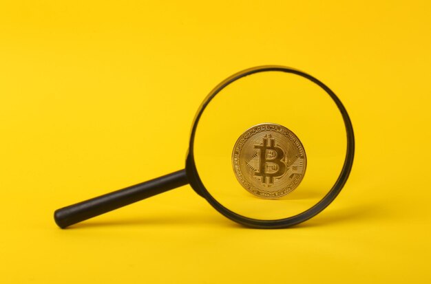 Bitcoin durch eine Lupe auf gelbem Hintergrund