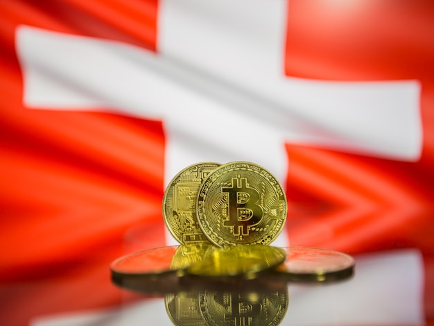 Bitcoin-Goldmünze und defokussierte Flagge des Schweizer Hintergrunds. Konzept der virtuellen Kryptowährung.