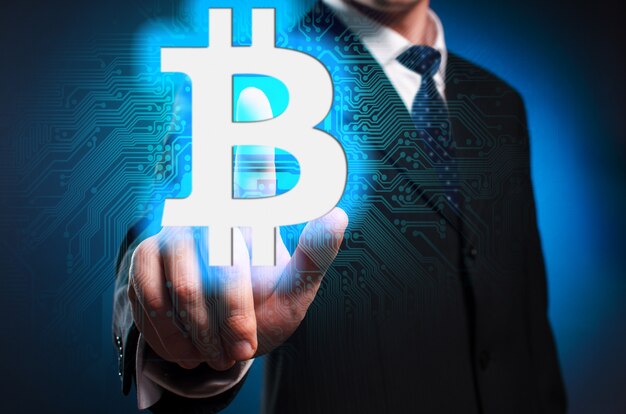 Bitcoin Un hombre con traje y corbata hace clic en el dedo índice en la pantalla virtual.