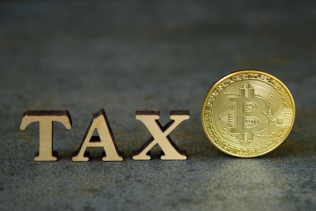 Foto bitcoin y junto a madera con letras tax. concepto de impuestos de bitcoin. moneda bitcoin de moneda criptográfica con mensaje de impuesto, concepto que determina la ley fiscal del dinero digital