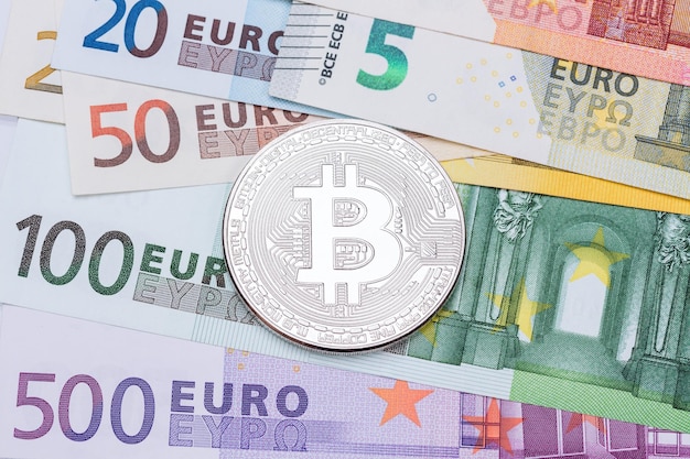 Bitcoin-Metallmünze über Euro-Banknoten Makrofoto