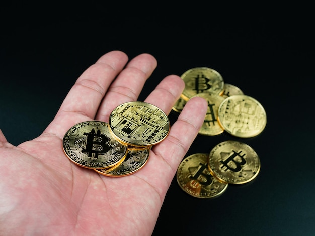 Bitcoin-Münze auf der Hand auf schwarzem Hintergrund platziert