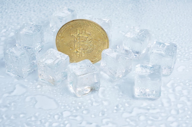 Bitcoin-Münze schmelzende Eiswürfel und Wassertropfen auf hellem Hintergrund.