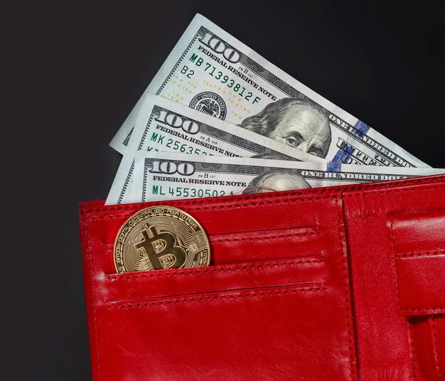 Bitcoin-Münze und US-Dollar in roter Brieftasche auf Schwarz, Nahaufnahme.