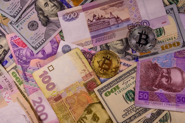 Bitcoin-Münzen auf den amerikanischen, ukrainischen und russischen Banknoten