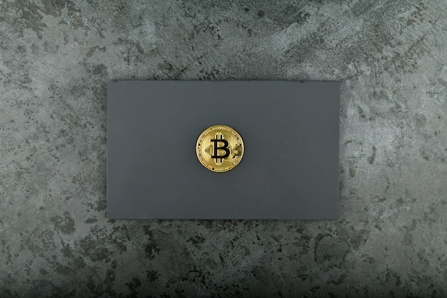 Bitcoin en un negro. Lugar para una inscripción. centavo de oro de bitcoin en mármol.