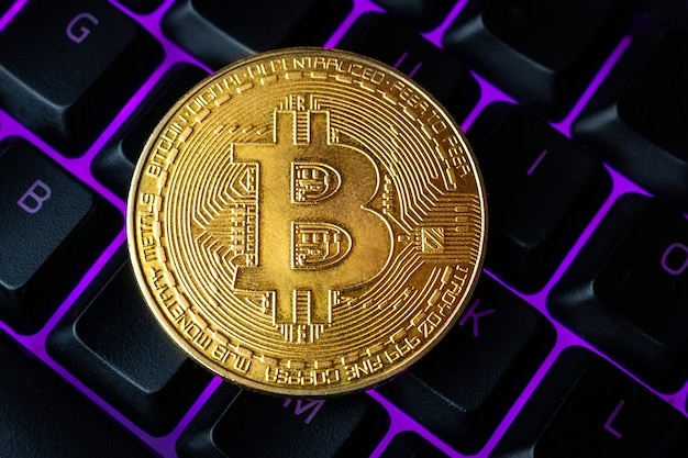 Bitcoin no teclado do computador no fundo, símbolo de dinheiro virtual eletrônico e conceito de criptomoeda de mineração. O bitcoin da moeda criptográfica encontra-se no teclado. Bitcoin no teclado.