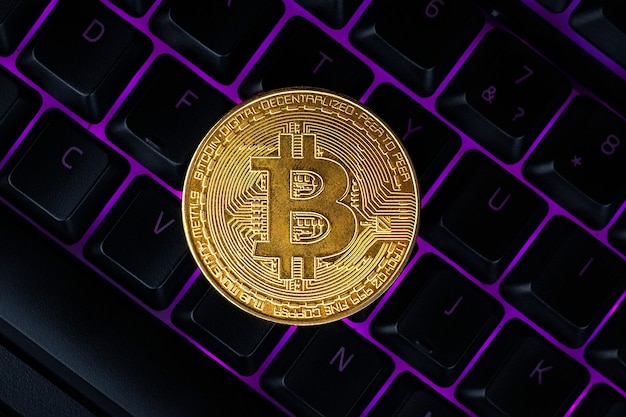 Bitcoin no teclado do computador no fundo, símbolo de dinheiro virtual eletrônico e conceito de criptomoeda de mineração.