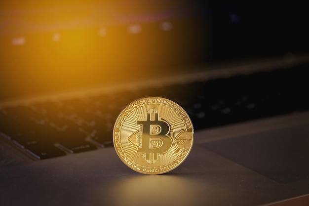 Bitcoin de oro en la computadora portátil con gráfico comercial en el fondo