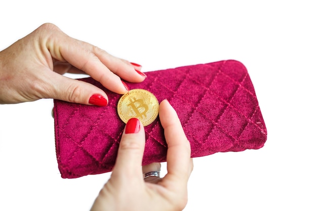 Bitcoin de oro de dinero virtual en dedos de monedero de tela de mujer rosa con uñas rojas en una moneda aislada sobre fondo blanco