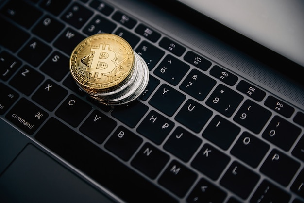 Bitcoin de oro en la pila de monedas, dinero digital en el teclado de la computadora. Concepto de negocio de criptomonedas