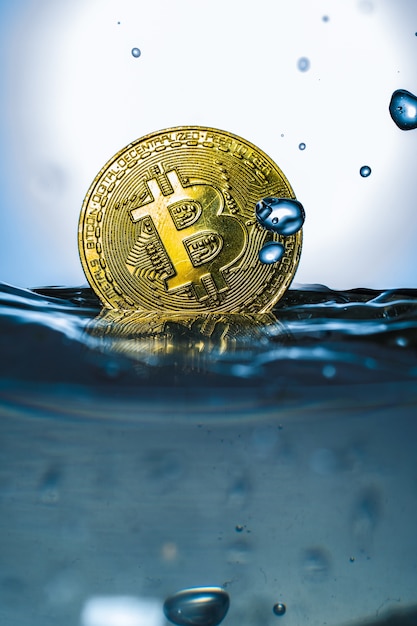 Bitcoin de oro con salpicaduras de agua sobre fondo blanco