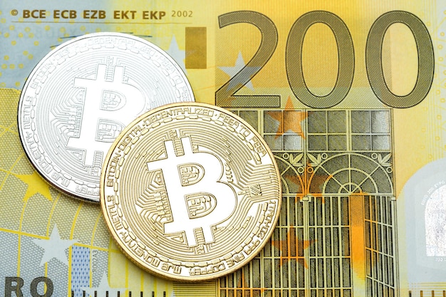 Bitcoin plateado y dorado sobre fondo de billetes de 200 euros